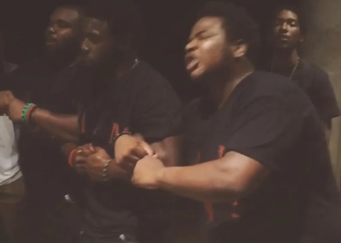 Several young people holding hands and arm wrestling in a dimly lit room, engaged in a friendly competition.