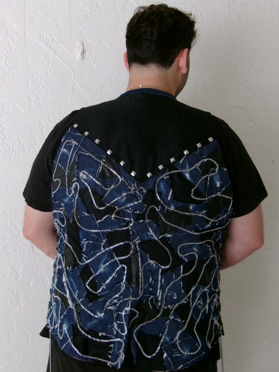 RODEO REBEL VEST – Faux leather vest with silk horse appliqué and reversible horse-print lining. Back features distressed denim, faux leather, and croc patchwork with chains and a studded yoke.