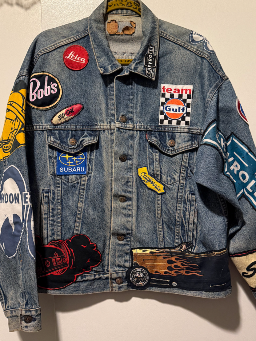 HOTROD REVIVAL JACKET – Upcycled Levi’s denim jacket reconstructed with repurposed T-shirts, shop shirts, and vintage patches. Finished with a graphic back panel and studded yoke.