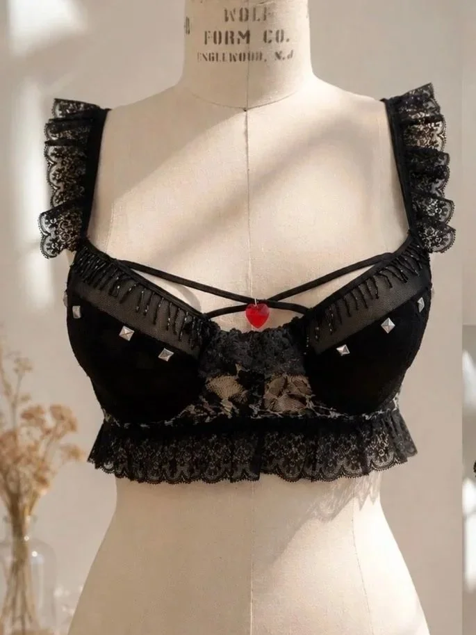 ROCKSTAR LACE LONGLINE BRA — A bold longline bra balancing structured support with a statement-making silhouette. Finished with black lace ruffles, beaded fringe, and stud accents, it fuses lingerie edge with rockstar attitude and sculptural fit.