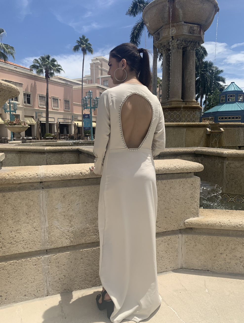 BELLA DRESS — A minimal front with a striking open-back design, this dress features arm and back cutouts adorned with hand-stitched pearls. Clean and elegant from the front, it reveals a bold, statement “party in the back” moment.