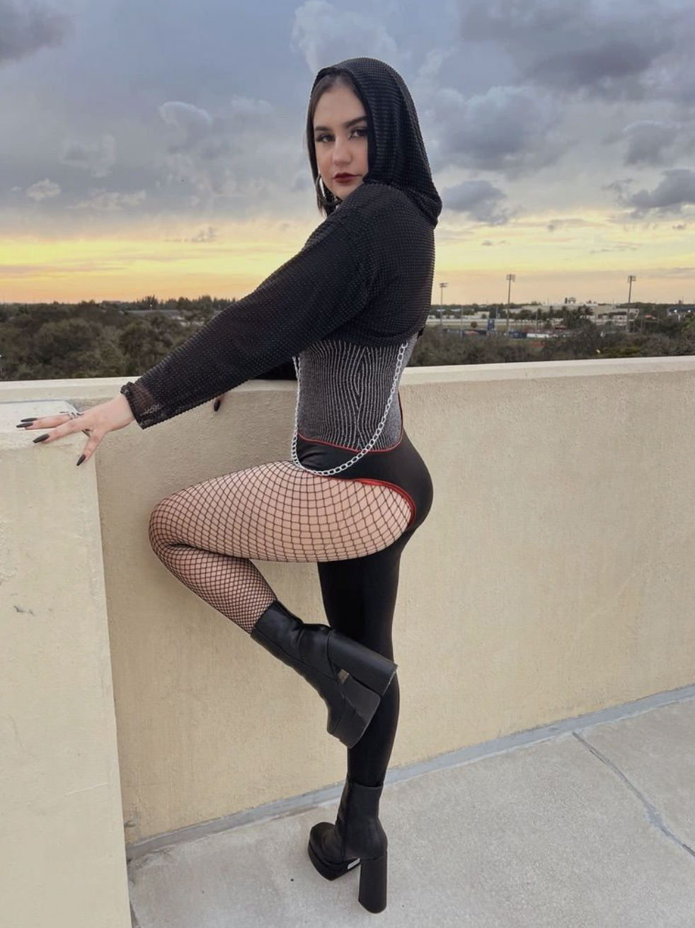 REPUTATION CATSUIT & HOOD — A bold one-legged bodysuit with a cropped diamond mesh hooded jacket. jacket inspired by Taylor Swift’s Reputation era. Crafted in stretch faux leather with red piping and reflective accents.
