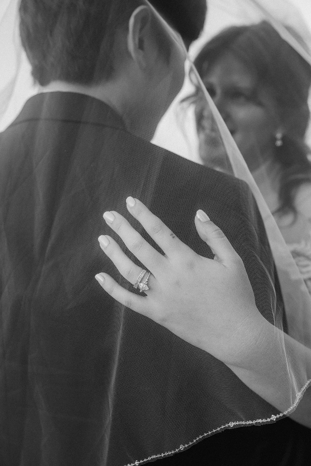 A bride and groom facing each other, with the bride's hand on the groom's shoulder, wearing a wedding ring, and the bride wearing a veil during Coronado Elopement.
