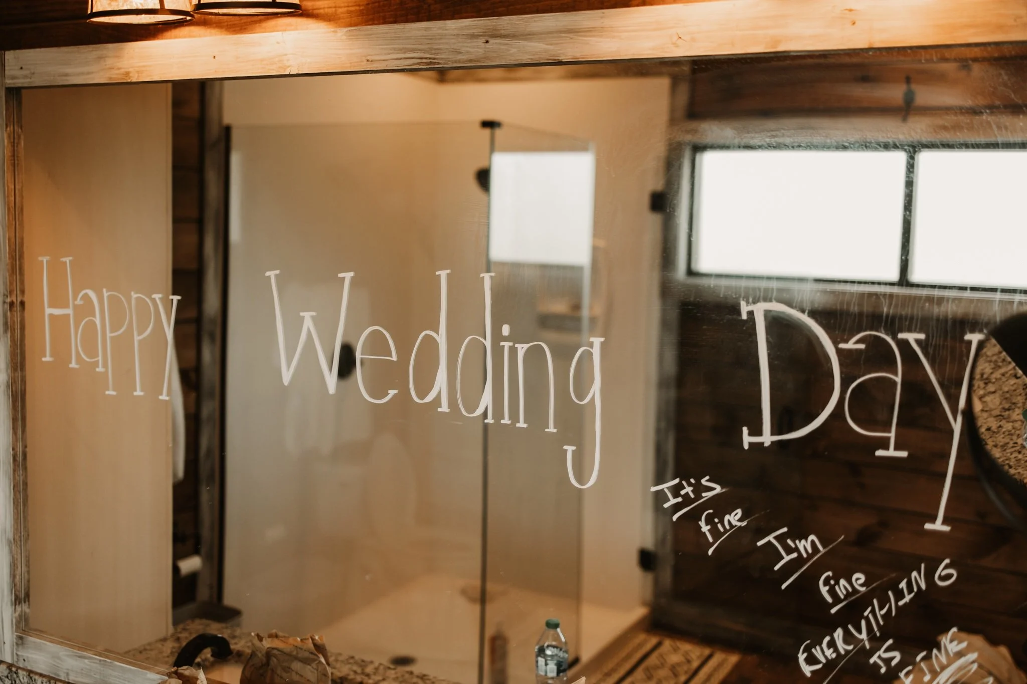 A wooden-framed mirror with handwritten birthday wishes on it. The mirror reflects part of a room with a window and a light fixture.