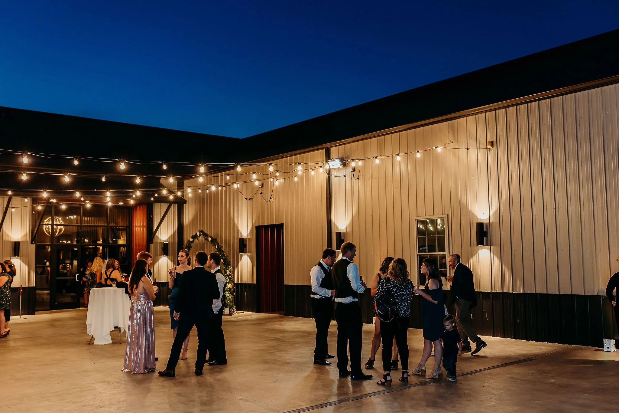 Guests dancing and socializing at an indoor evening event with string lights hanging from the ceiling.