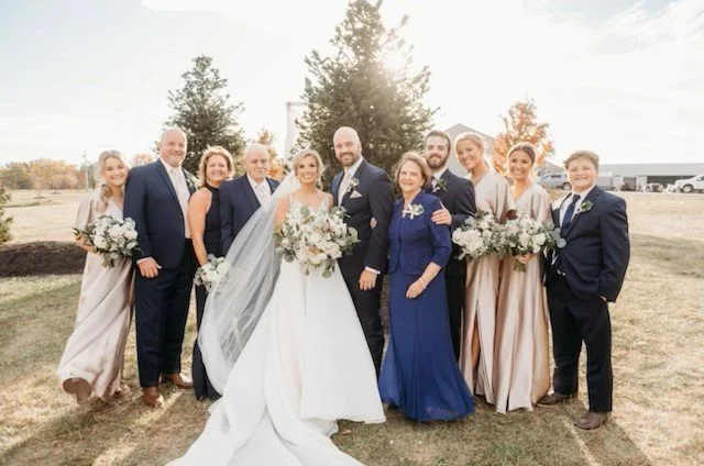 Wedding party outdoors with the bride, groom, bridesmaids, and groomsmen posing together.