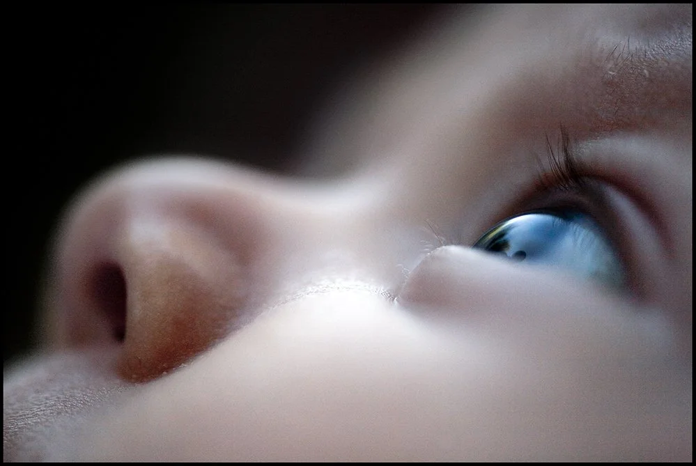 Close-up of a child's face focusing on the nose and eye, with the eye looking slightly upward.