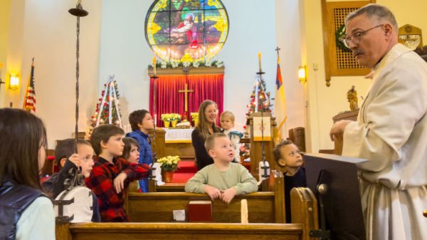 Children seated in church pews listening to pastor