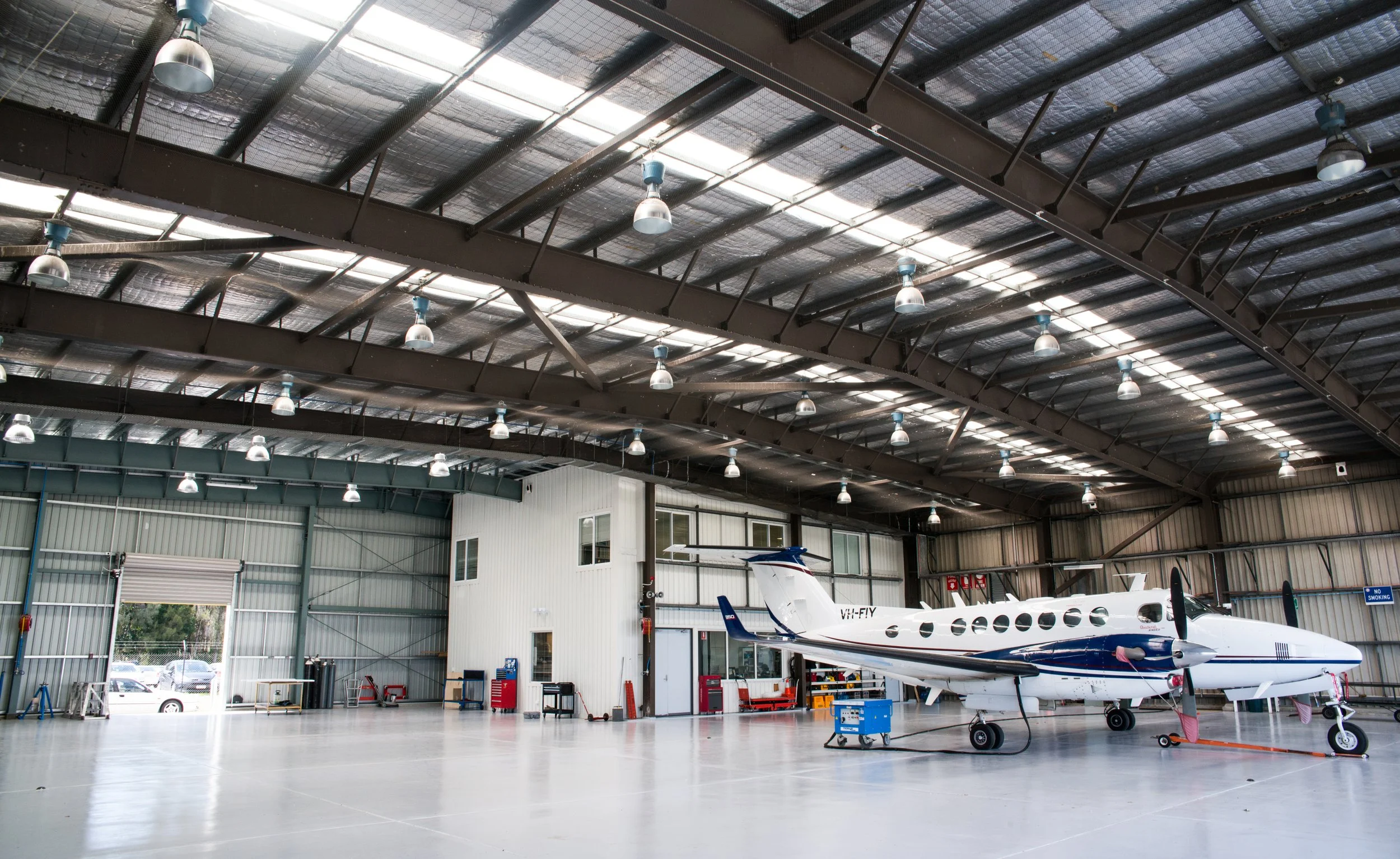 Inside an aircraft hangar with a small private jet aircraft parked on clean concrete floor.
