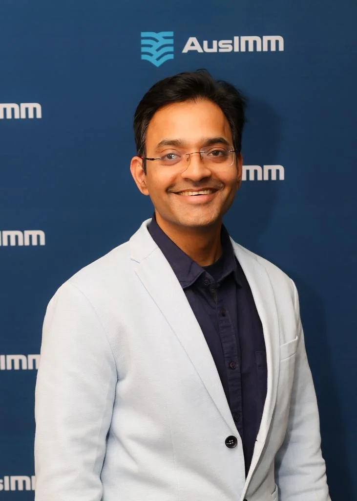 Sushant, smiling in front of a blue backdrop with the AUSIMM logo.