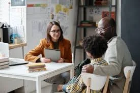 A young woman and a young boy talking to an older man in an office or classroom setting.