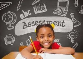 A young girl smiling at a desk with a blackboard background featuring educational doodles and the word 'Assessment' in the center.