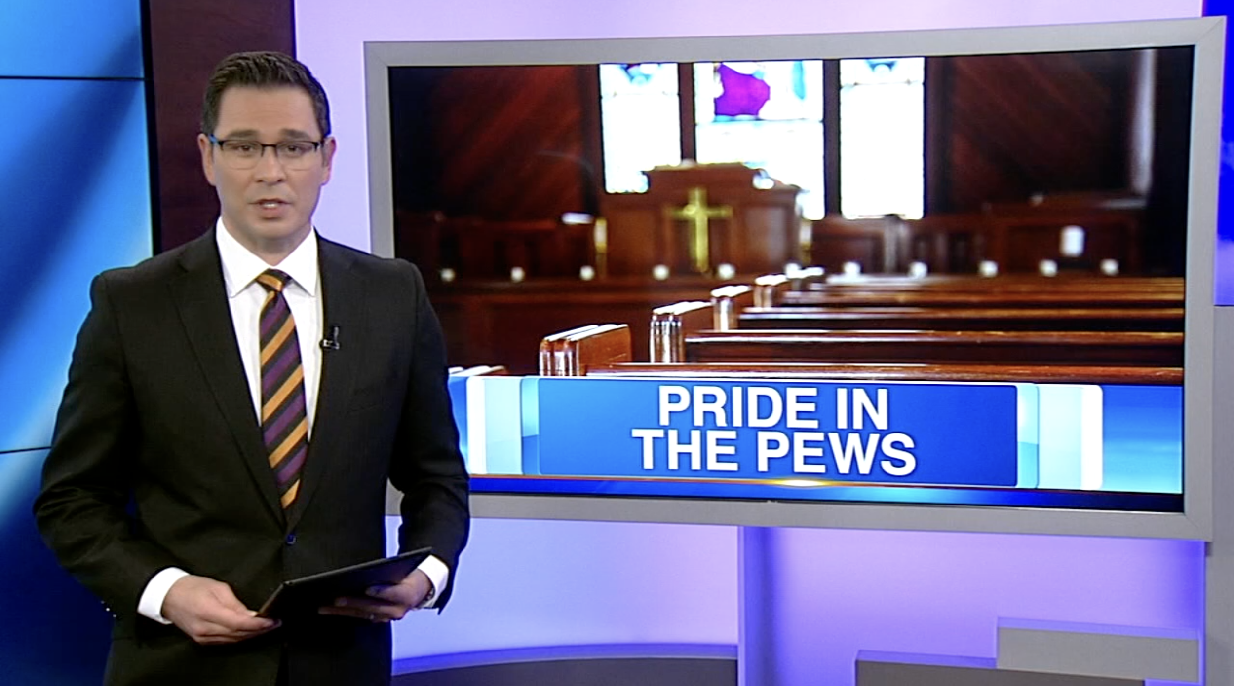 News anchor standing in front of a screen displaying a church interior with pews and a cross, with a headline that reads 'Pride in the PewS'.