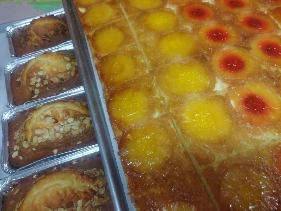Close-up of a variety of baked goods, including pineapple upside-down cake slices and cherry-topped desserts.