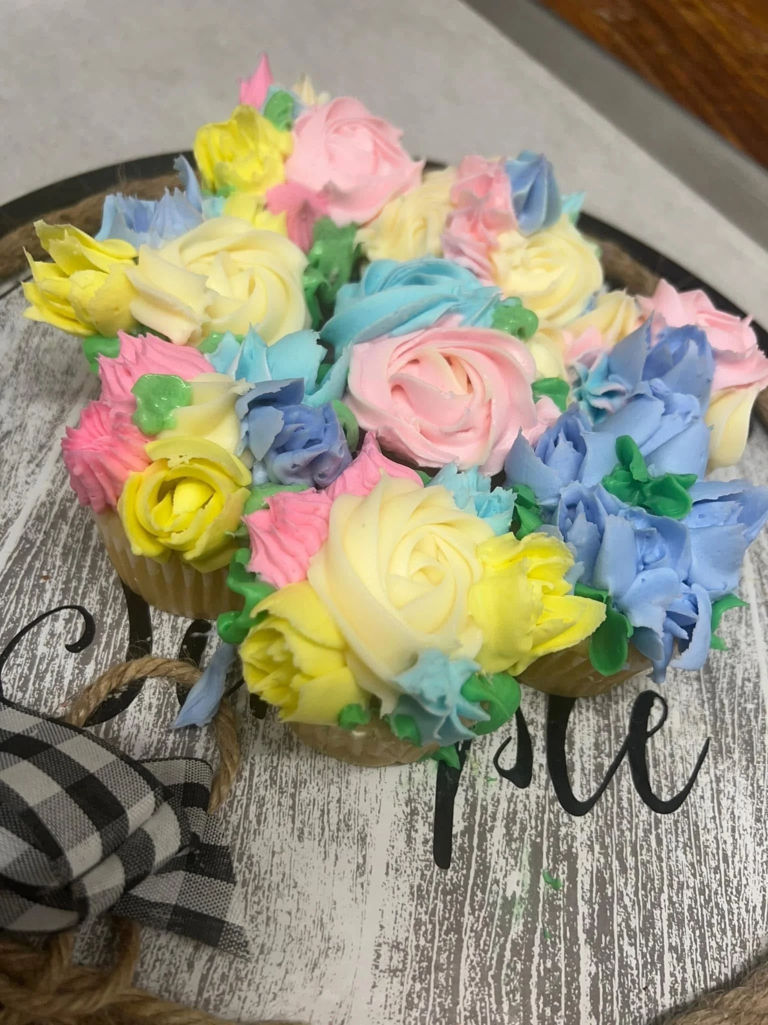 Colorful buttercream roses in pink, blue, yellow, and green on a cake.