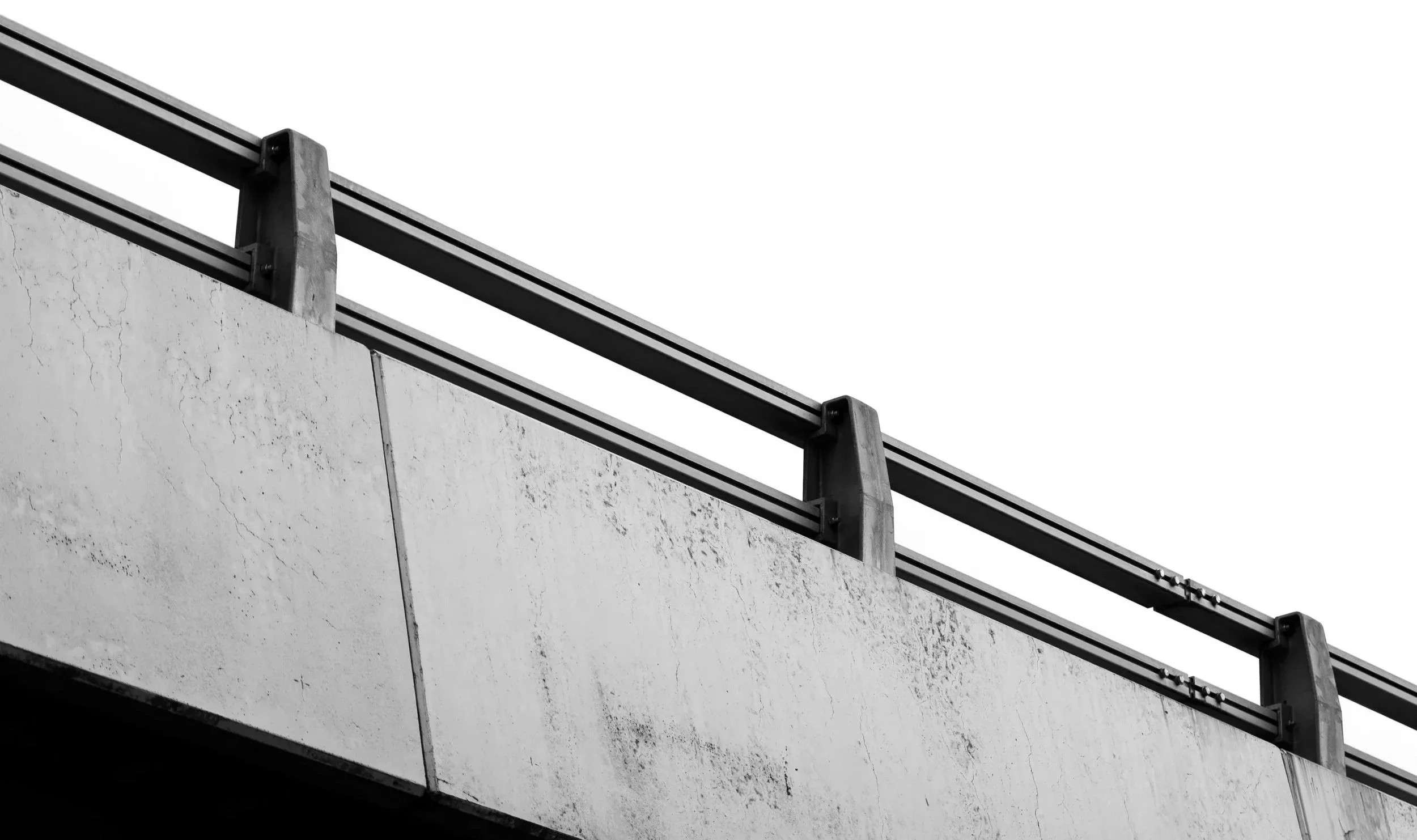 Close-up of a concrete bridge or overpass with metal railing, black and white photo.