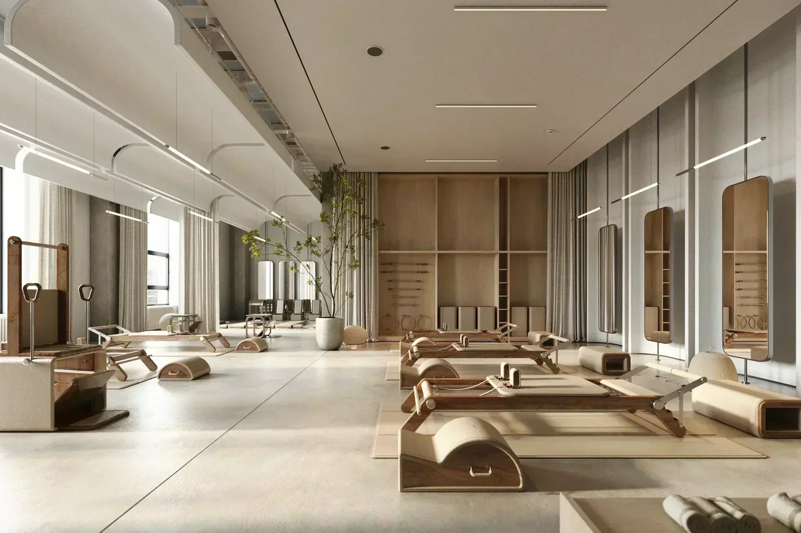 Modern Pilates or yoga studio with wooden equipment, mirrors on wall, and natural light from windows.