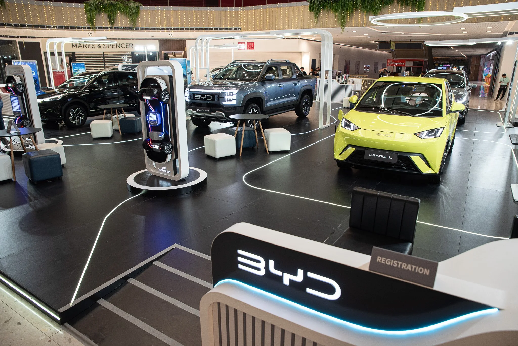 Electric cars on display at a shopping mall showing BYD's new vehicle models and featuring a registration desk.