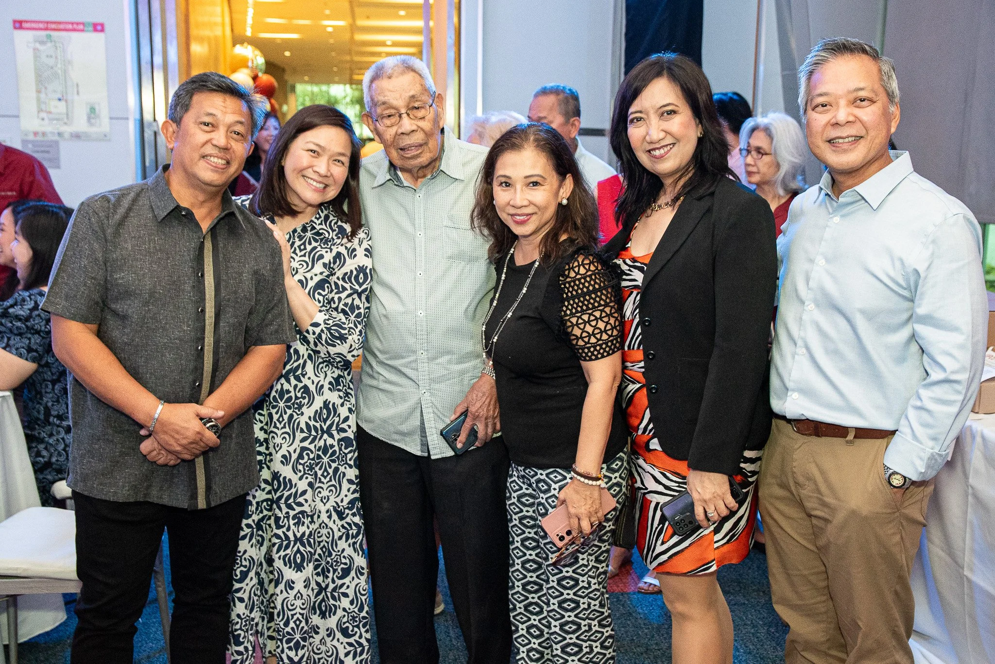 Group of seven people at a social event, smiling and posing for a photo indoors.