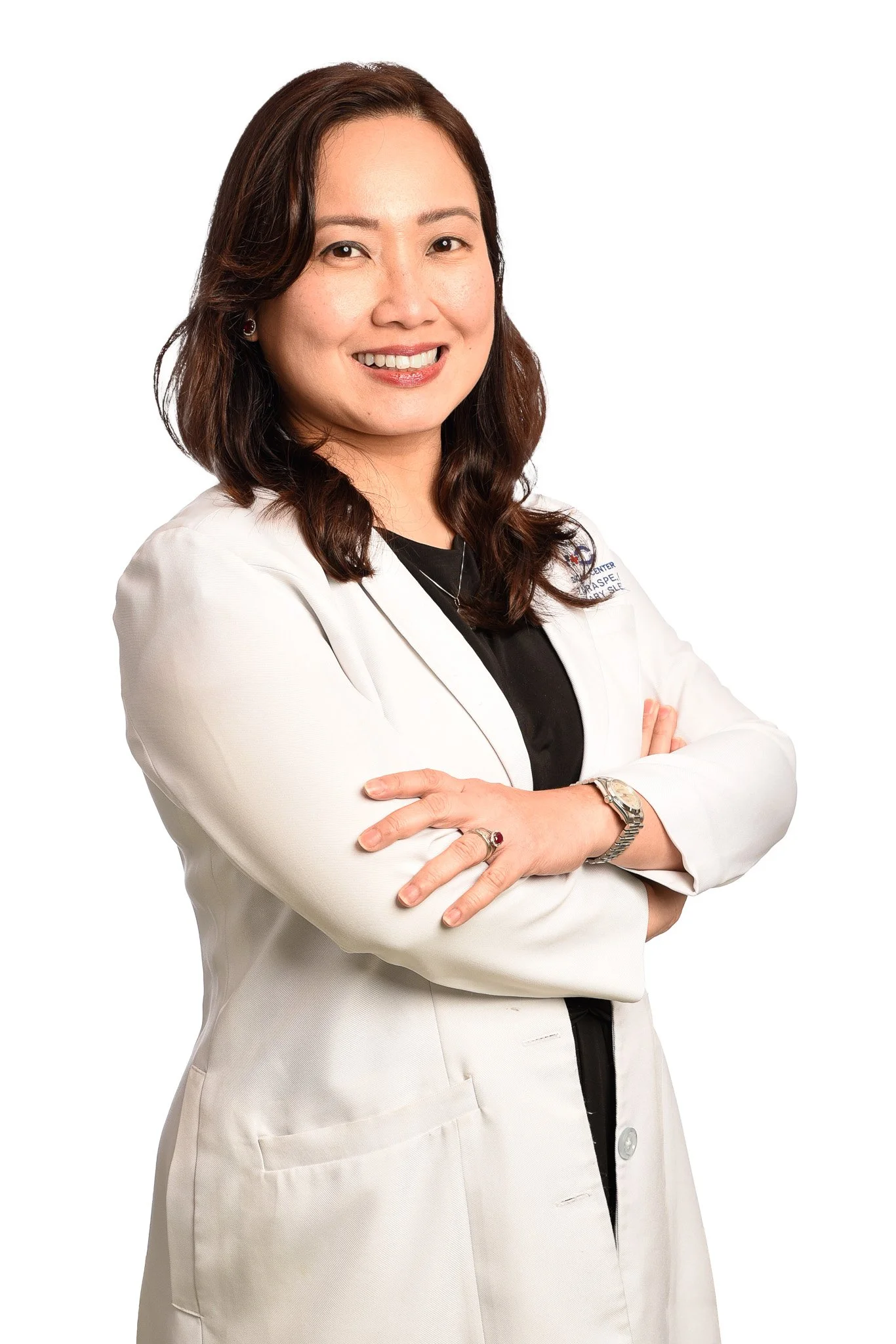 A woman with shoulder-length brown hair, smiling, wearing a white medical lab coat with arms crossed, against a white background.