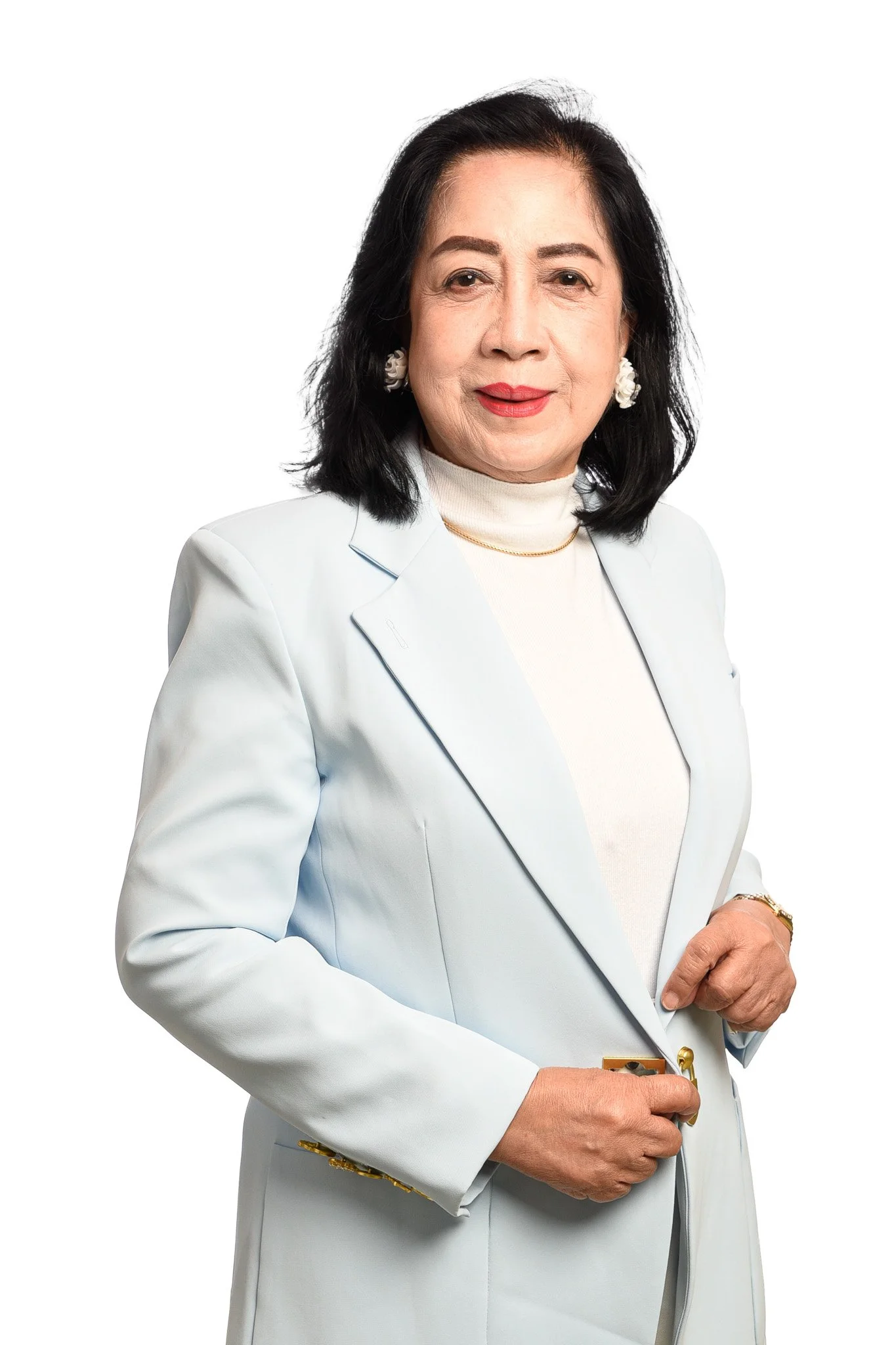 A woman with black hair and red lipstick wearing a white blazer over a white turtleneck, standing against a plain white background.