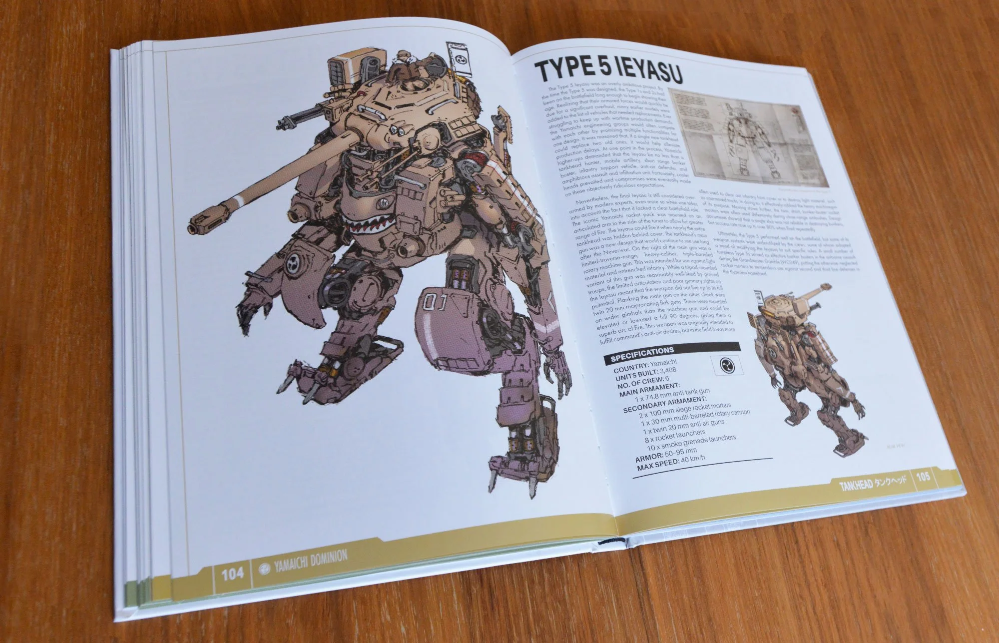 Open book showing illustration of a tan-colored mechanized tank robot with weapons and a small humanoid figure on top, with technical details and specifications on the opposite page.
The book is TANKHEAD Mechanical Encyclopedia.