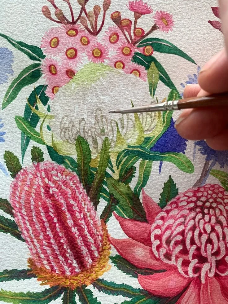Artist painting a watercolor of various pink flowers and green leaves on textured paper.