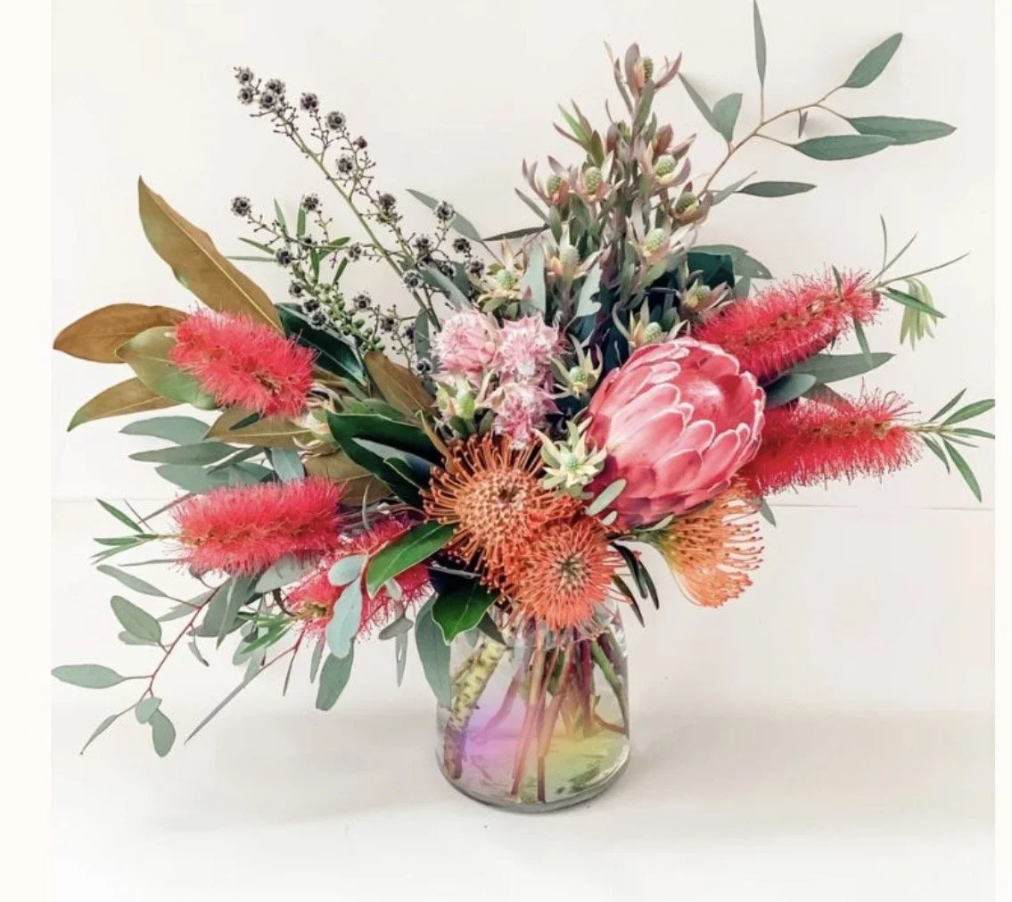 Colorful flower arrangement with pink, red, and orange blooms in a glass vase