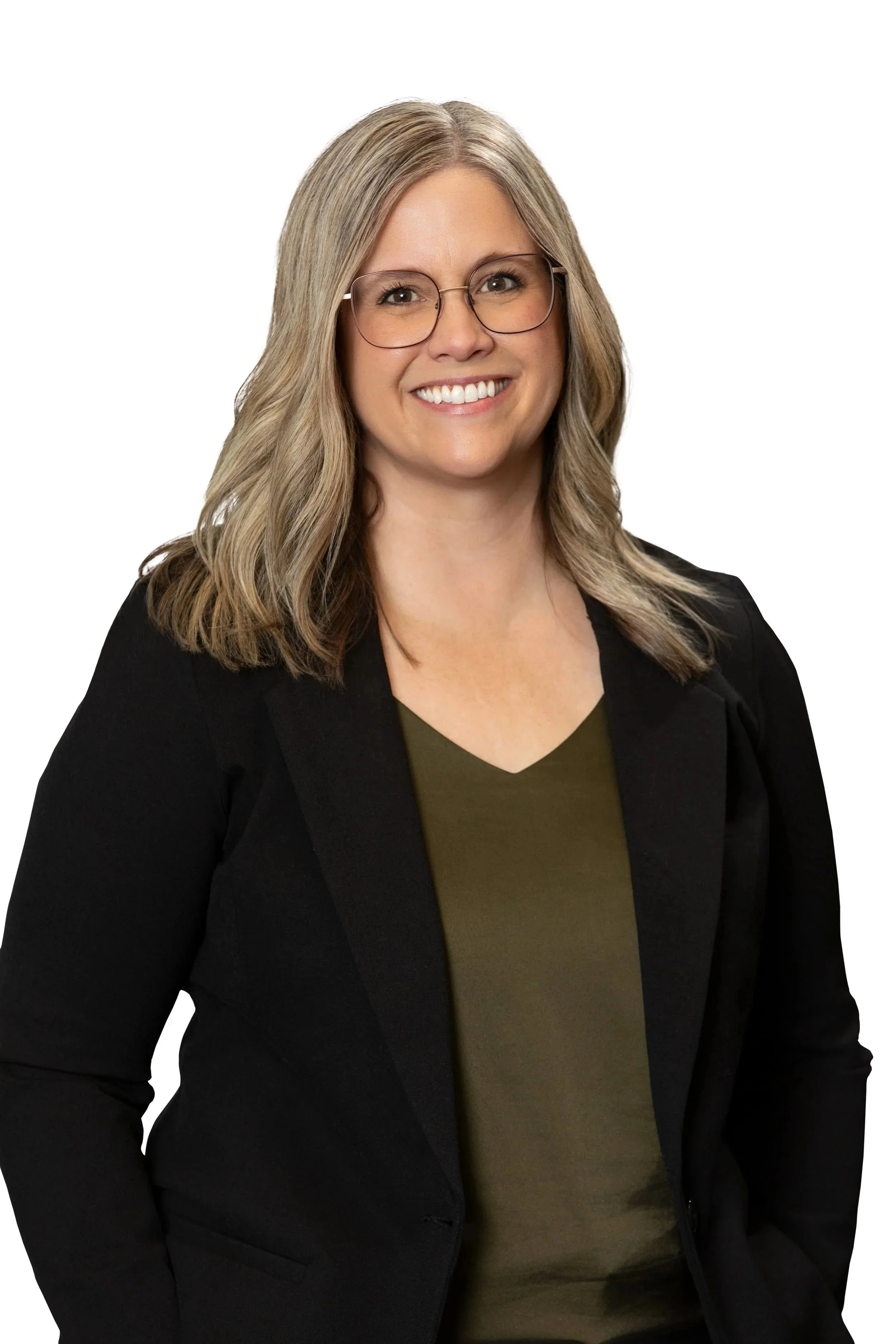 A woman with shoulder-length blonde hair, glasses, and a friendly smile, wearing a black blazer and an olive green top, standing against a white background.