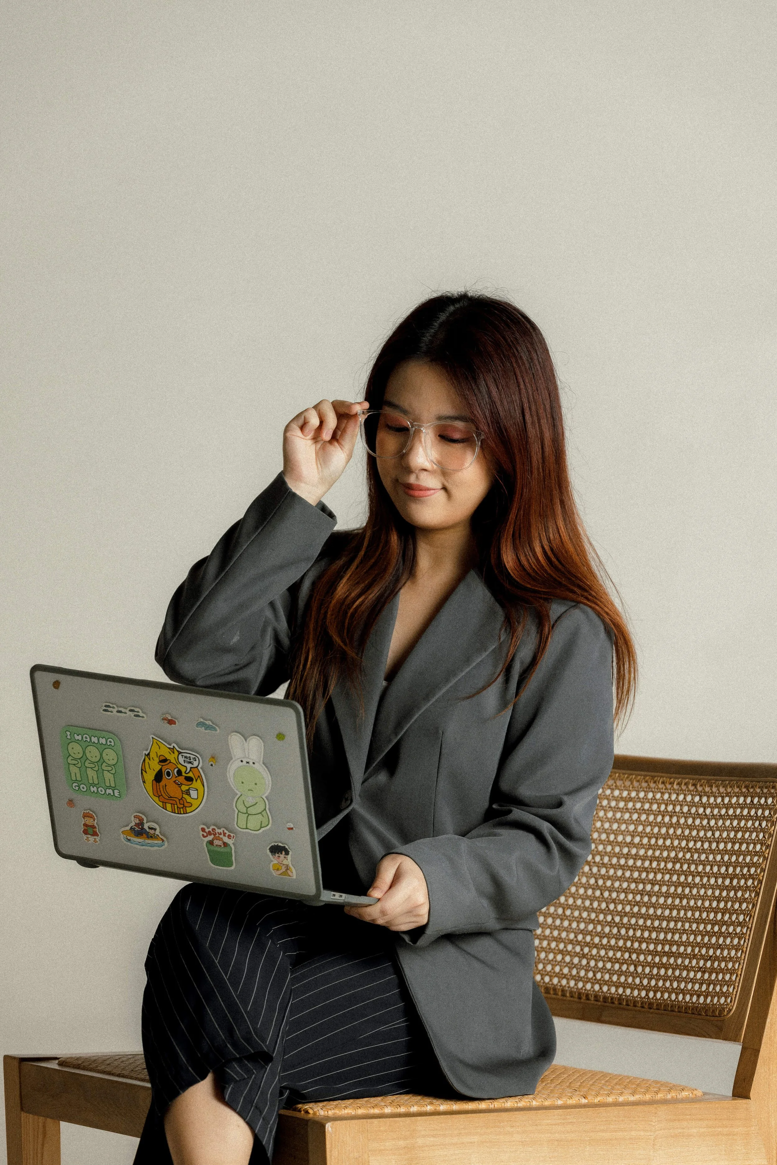 Ying sitting on a wooden bench, looking down at her laptop with a slight smile.