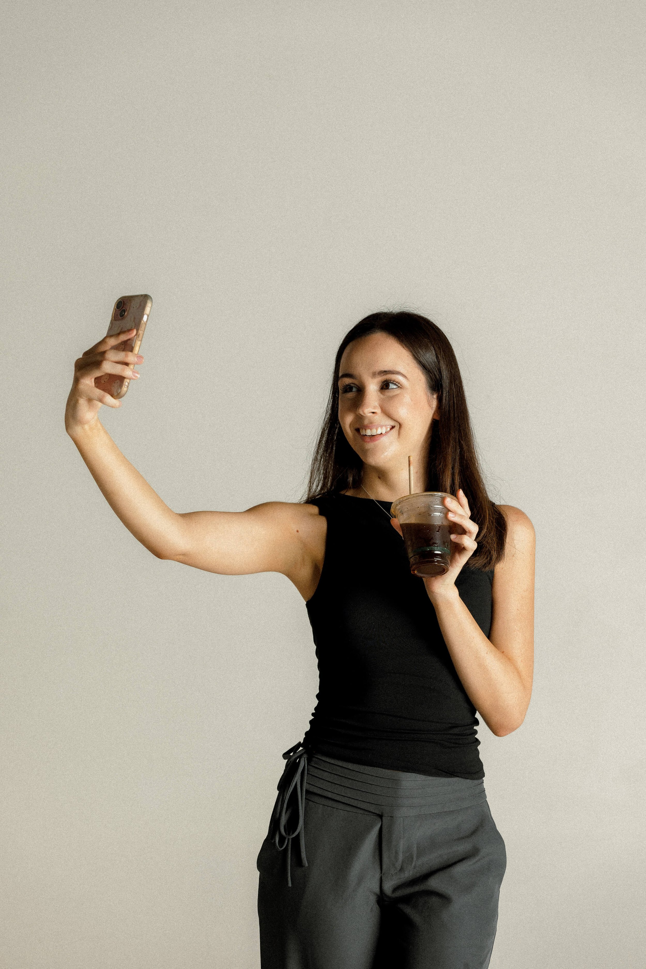 Isobel taking a selfie while holding an iced coffee, smiling.