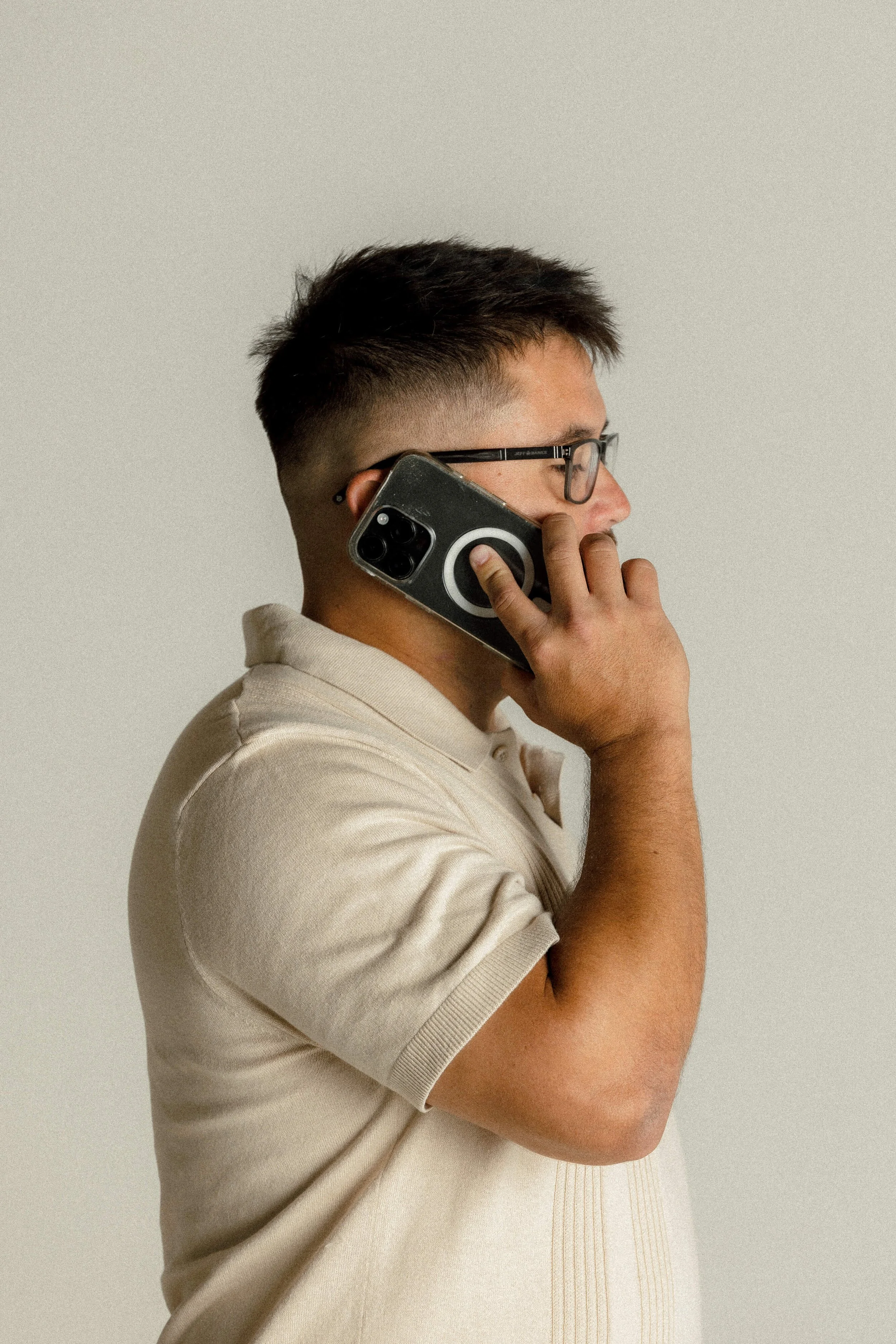 Matt talking on a smartphone, wearing a beige polo shirt.