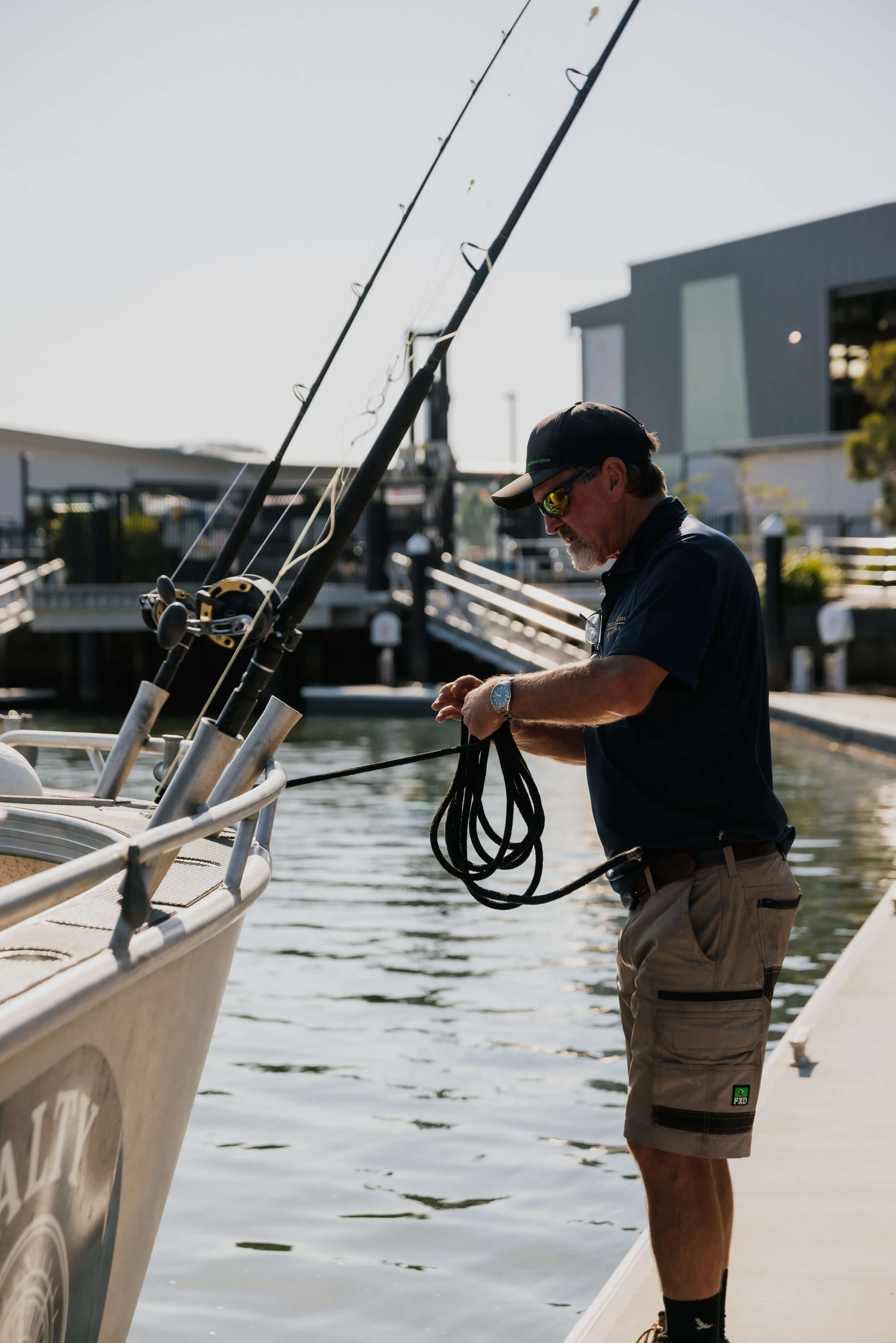 A man preparing a boat docked in water at a marina.