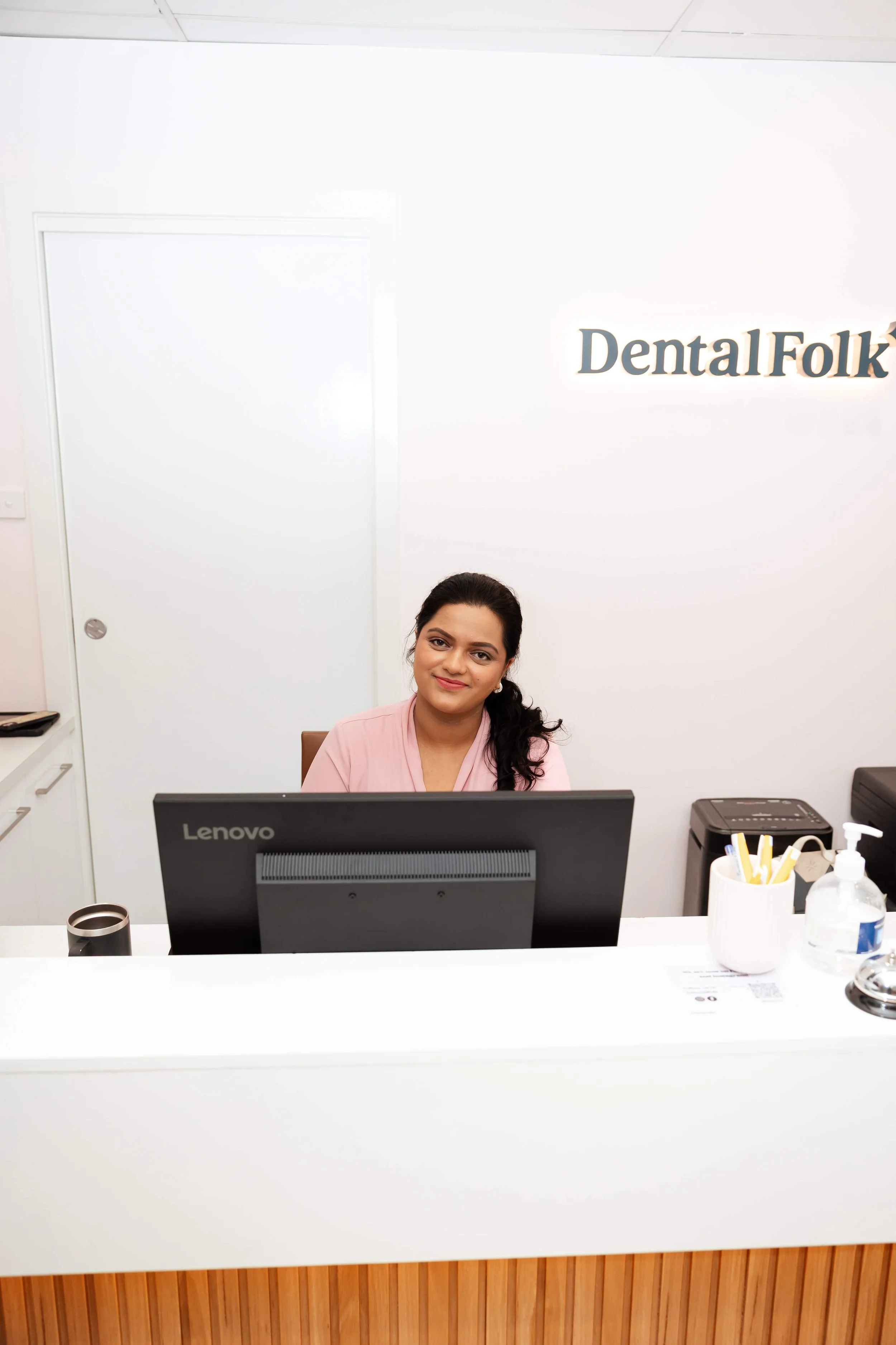 A smiling receptionist behind a computer.