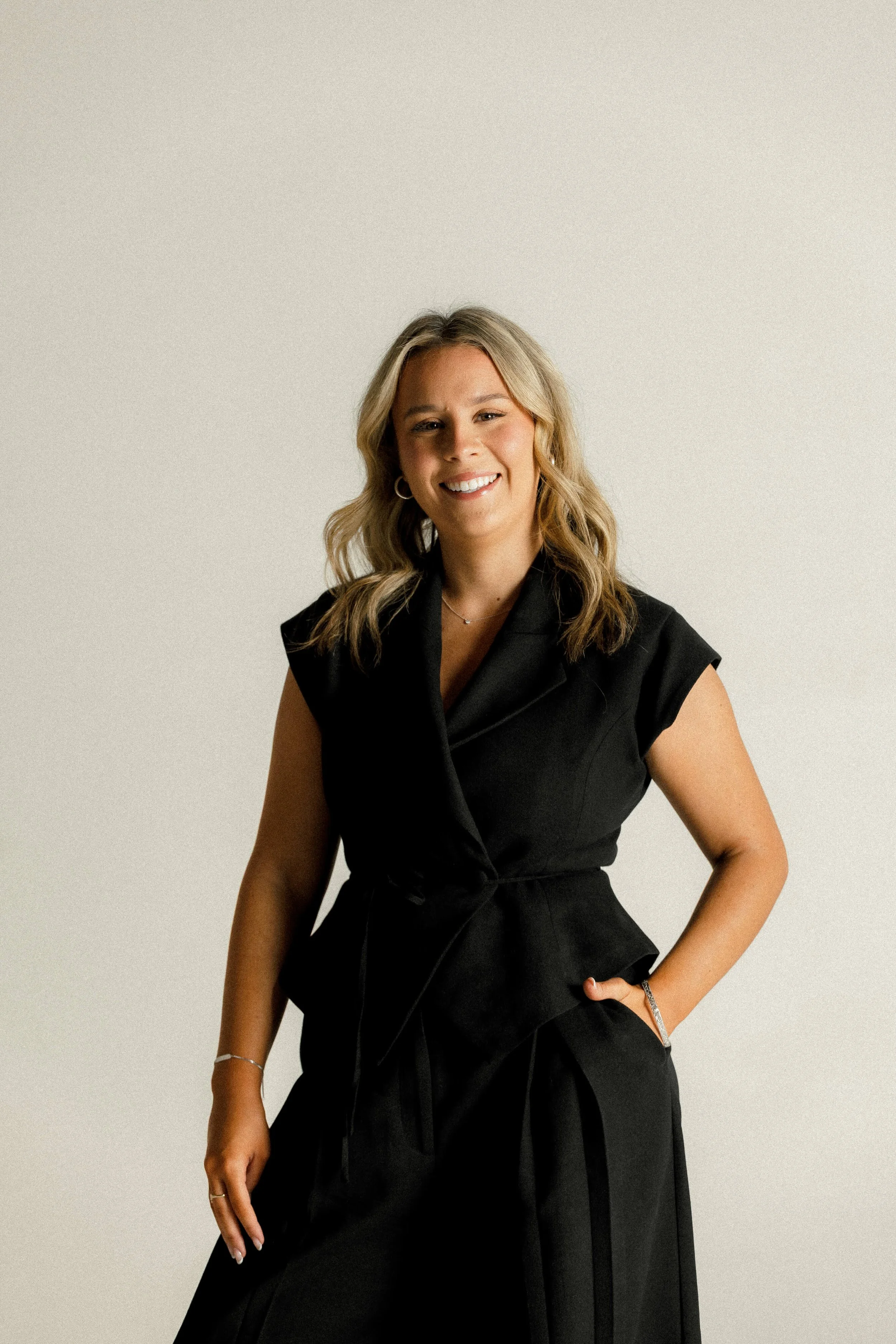 Ciara stands in a professional pose smiling with one hand in her pocket.