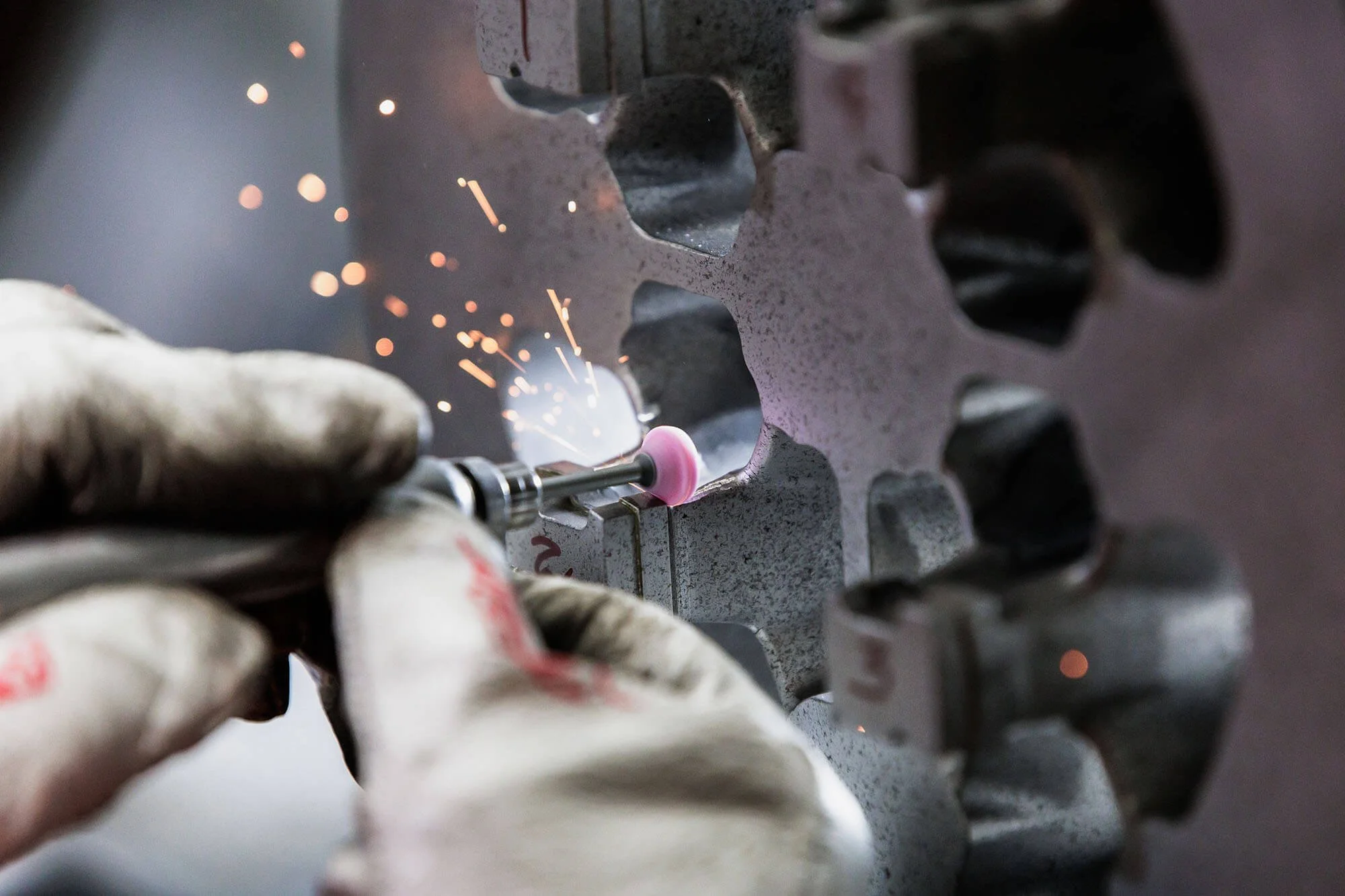 A close up of a tool making sparks fly and working on a piece of metal.
