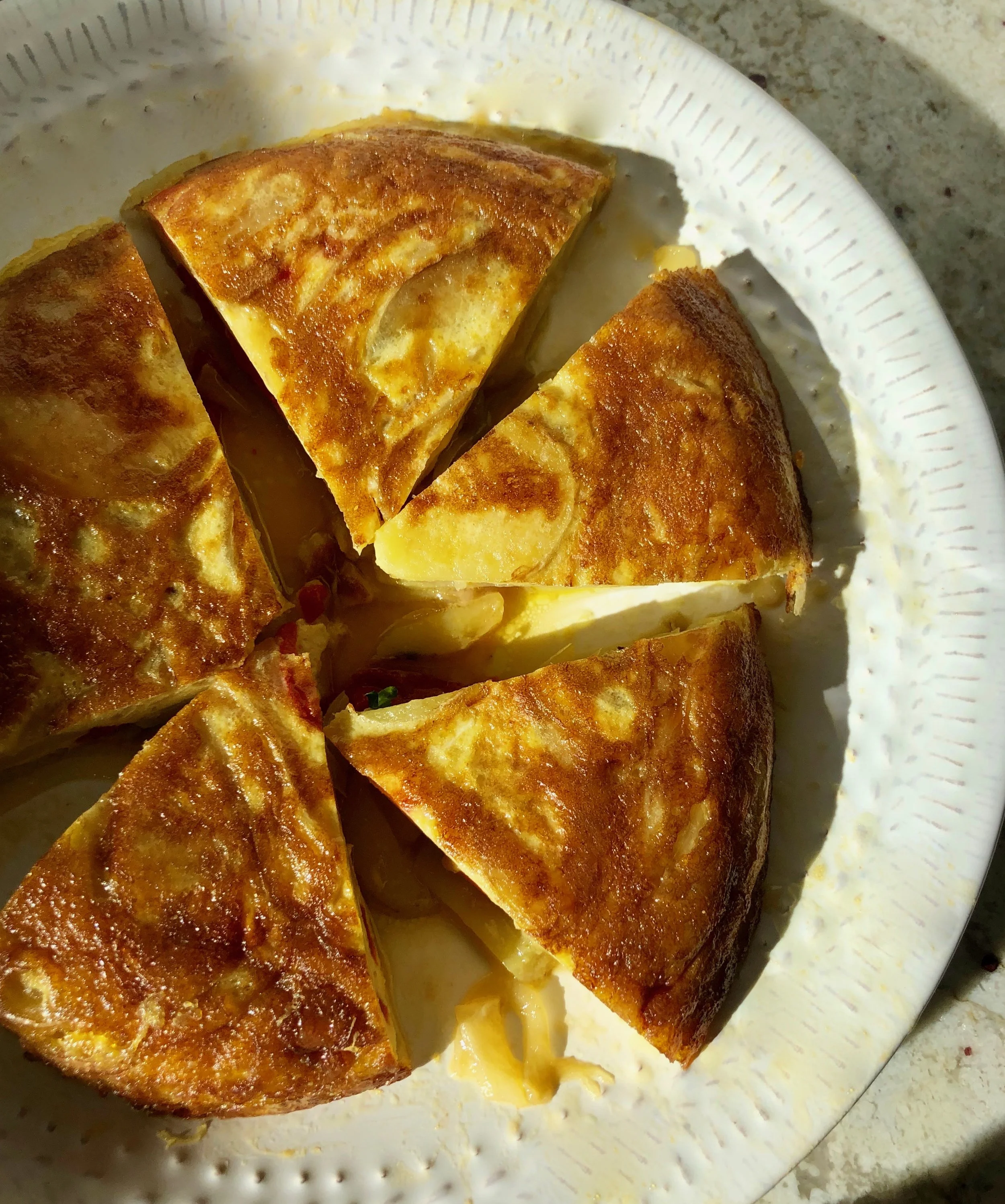 Fried cheese quesadilla cut into four wedges on a white plate with melted cheese visible inside.