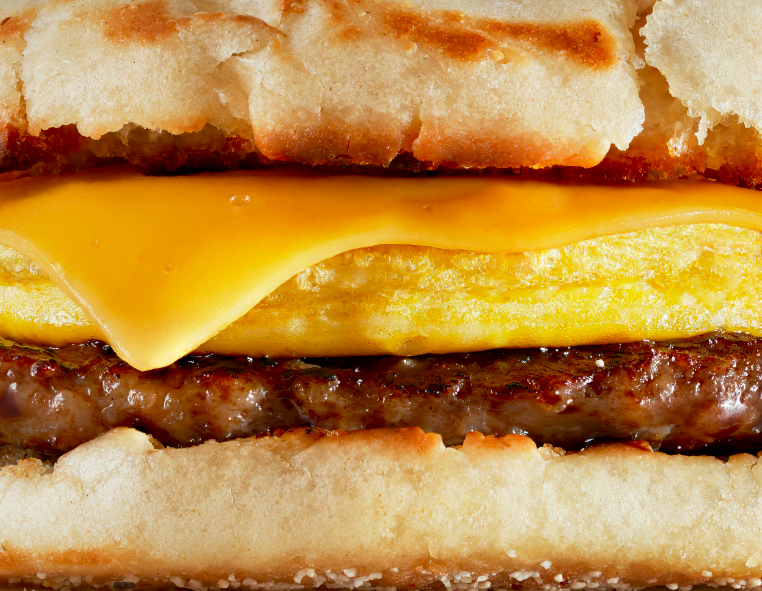 Close-up of a cheeseburger with a beef patty, melted cheddar cheese, a fried egg, and toasted bun.