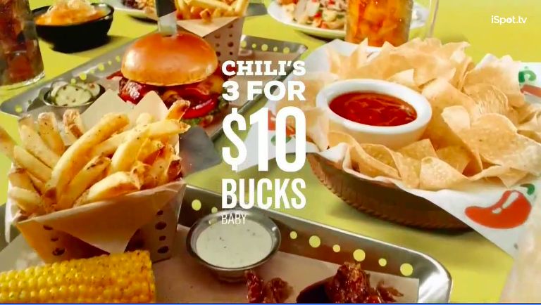 Restaurant table with fries, corn on the cob, chips with salsa, and a hamburger, with promotional text for Chili's 3 for $10 offer.