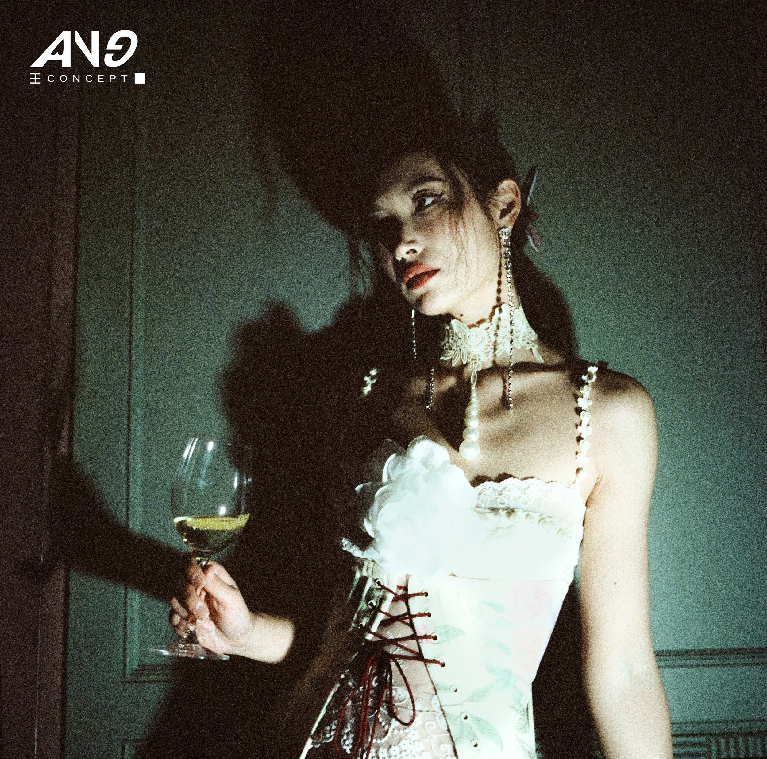 A fashion influencer wearing lace jewelry and a glamorous corset-style dress holds a wine glass in a dimly lit room at Chapel Bar in New York.