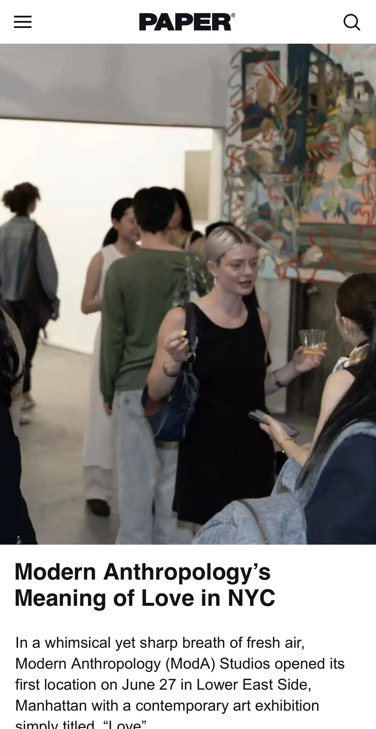 Group of people gathered at Modern Anthropology's art exhibition in NYC, with a woman in black holding a drink and talking.