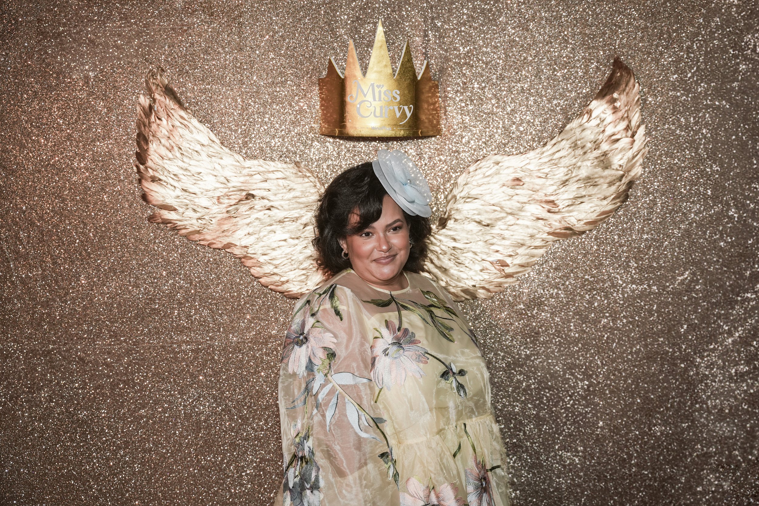 Female VIP guest captured in front of the custom photo wall of dating app WooPlus' Miss Curvy Pageant NYFW runway show by event production agency ANG Concept.