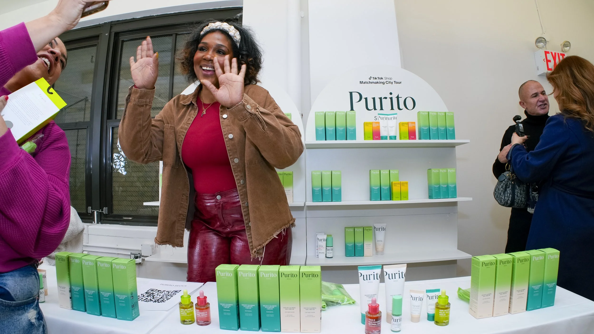 A host woman from Purito smiling and waving at a TikTok KOL's camera at the TikTok Shop Matchmaking City Tour 2025, a three-weekend activation by event production agency ANG Concept in New York.