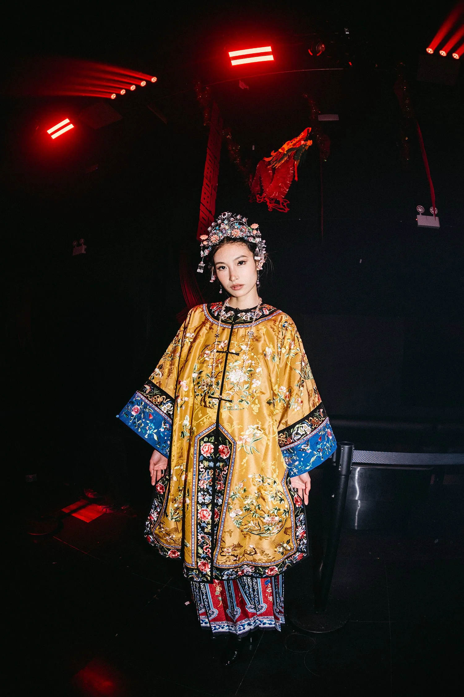 A fashion content creator in traditional Chinese attire standing in a dimly lit setting at experiential production agency ANG Concept's Lunar New Year Party.
