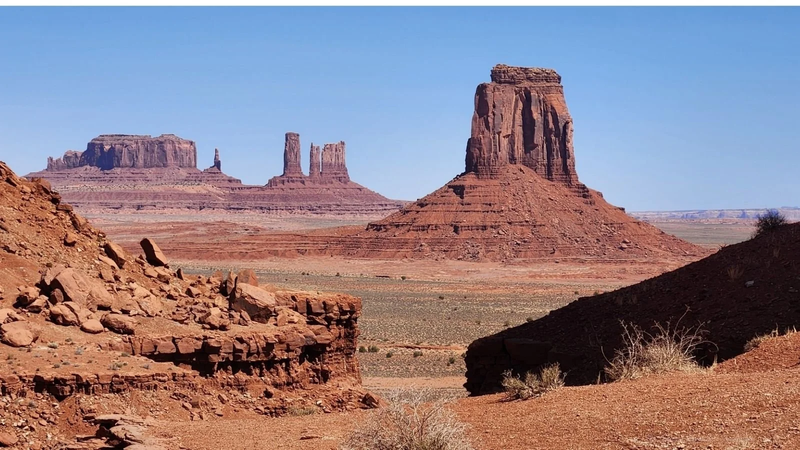 A desert landscape with towering red rock formations under a clear blue sky.