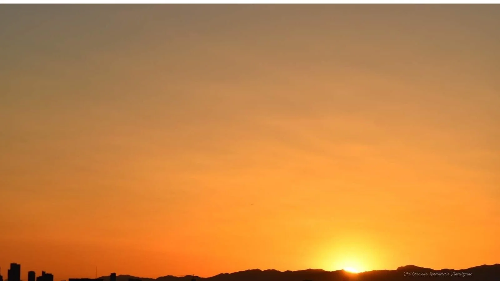 Red, orange, and yellow sunset over a distant mountain range.