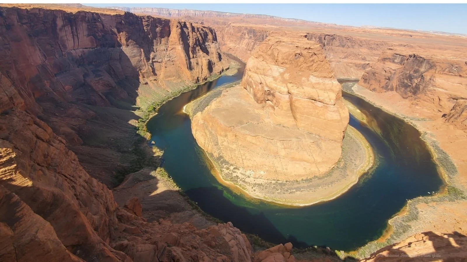 A wide shot of Horseshoe Bend showing the Colorado River forming a horseshoe-shaped bend through reddish-brown canyon walls.