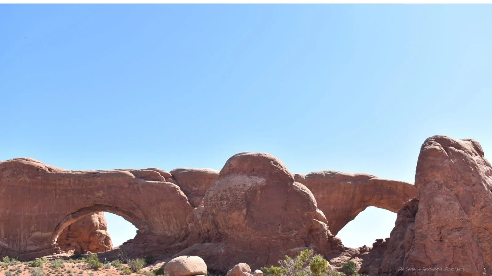 Rock formations and natural arches in a desert landscape under a clear blue sky.