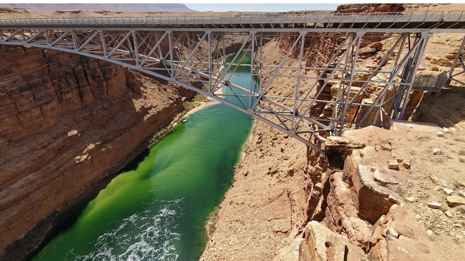 A bridge over a canyon with green water below.