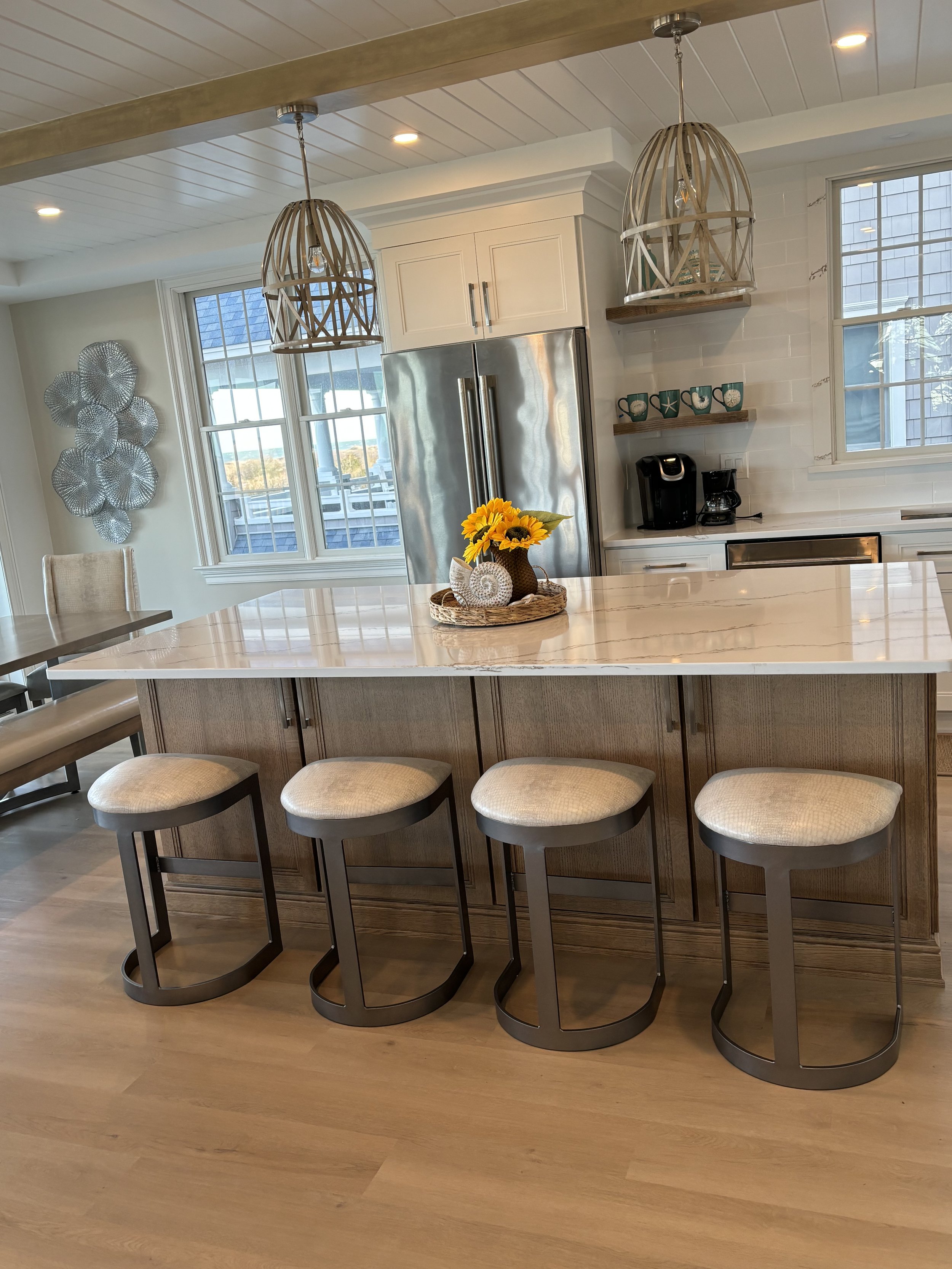 Bright kitchen with large island, barstools, white cabinetry and floating shelves
